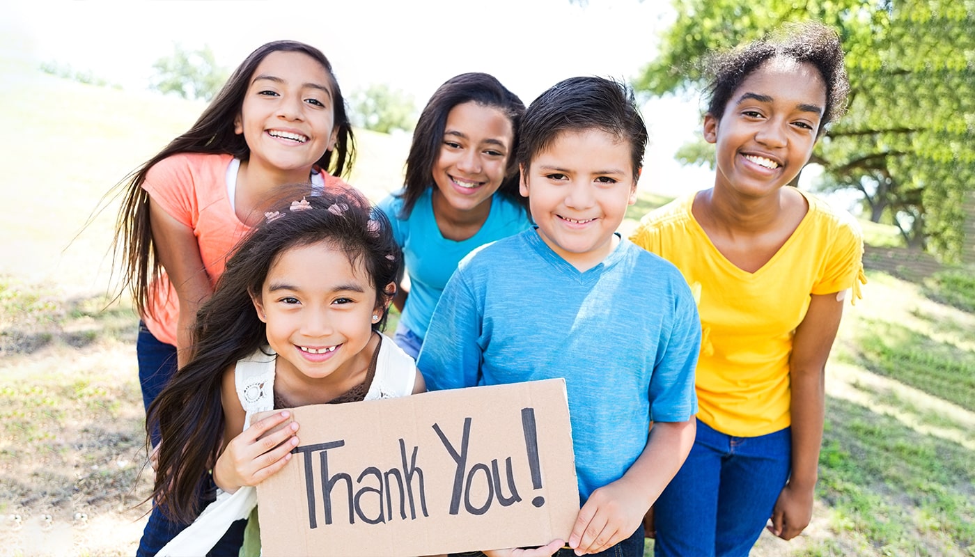 Five smiling children are holding a sign that says thank you.