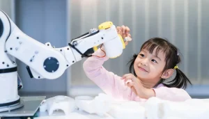 A young girl smiles up at a robot while she touches its hand.
