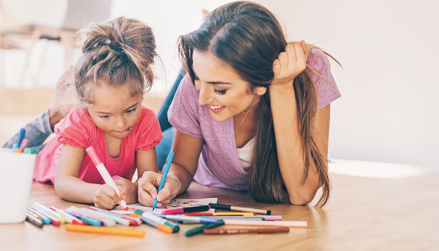 A mother and daughter work on February coloring sheets together.