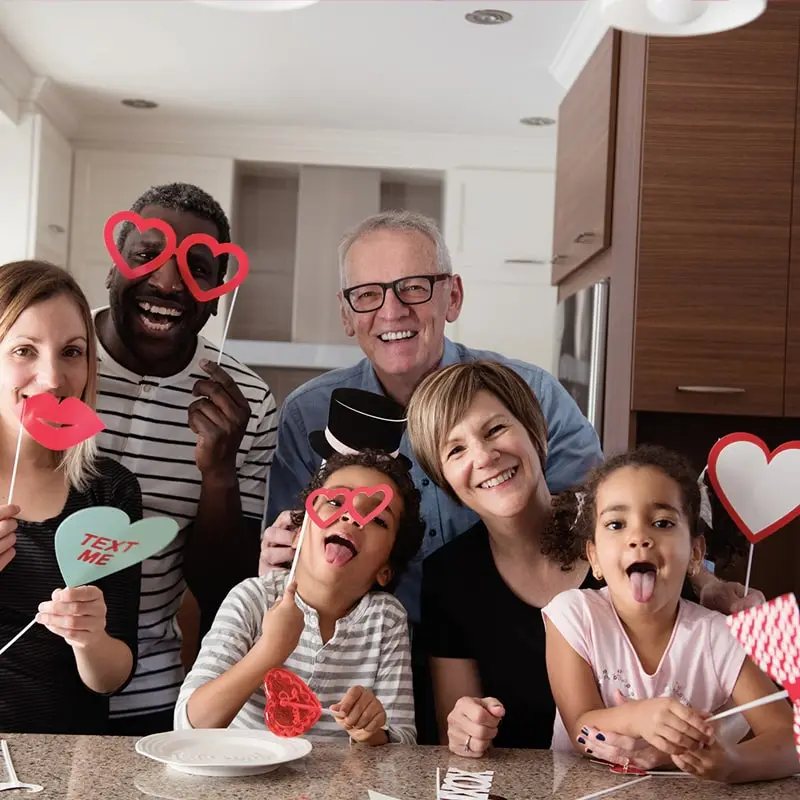 A multi-generational and multi-racial family poses with Valentines and big smiles in their home.