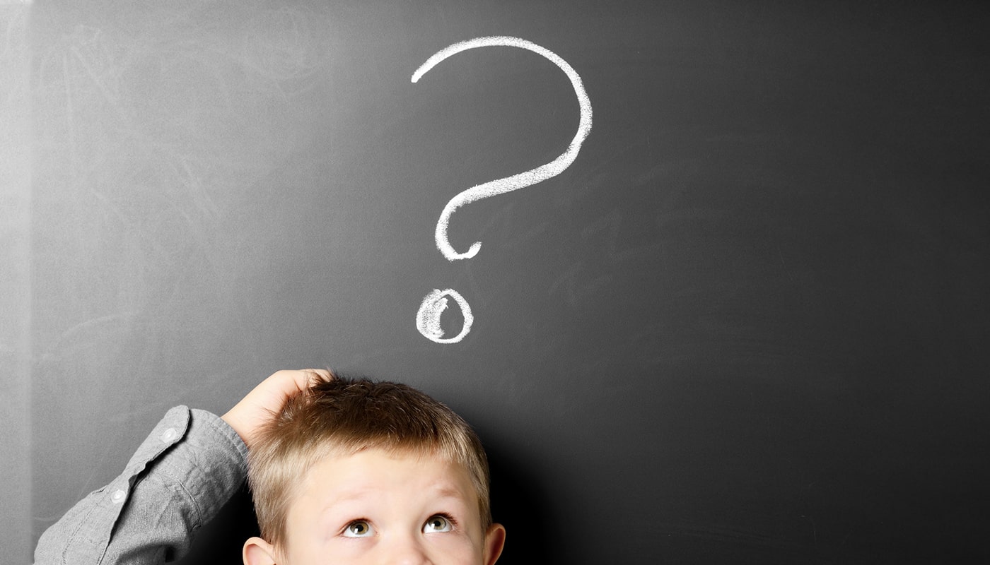 A little boy with a question mark drawn on a chalk board above his head.