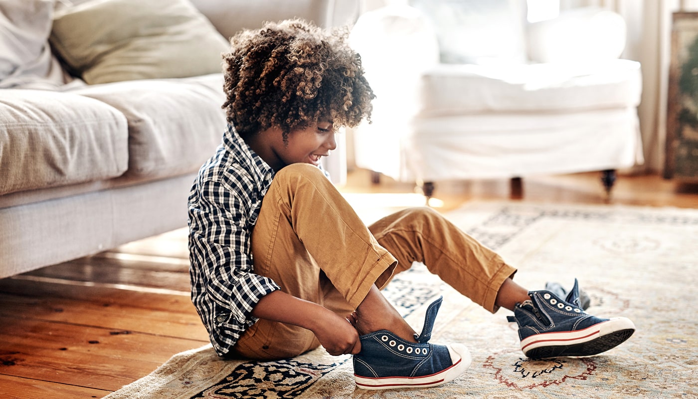 a young boy sitting in a living room putting on his shoes