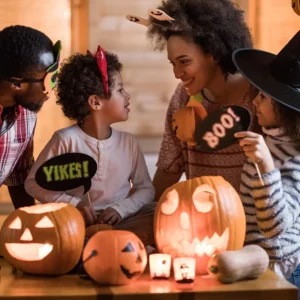 Mom, dad, daughter and son gather around the jack-o-lantern for Halloween fun.