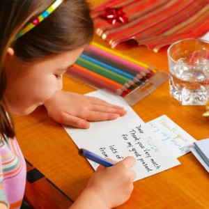 A young girl is writing a thank you note.