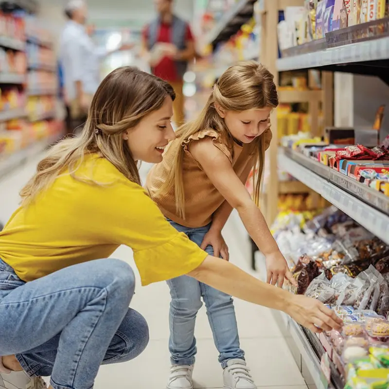 Mom and daughter are grocery shopping as they complete their reverse advent calendar for giving to a food pantry.